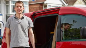 Man smiling and stood next to his van