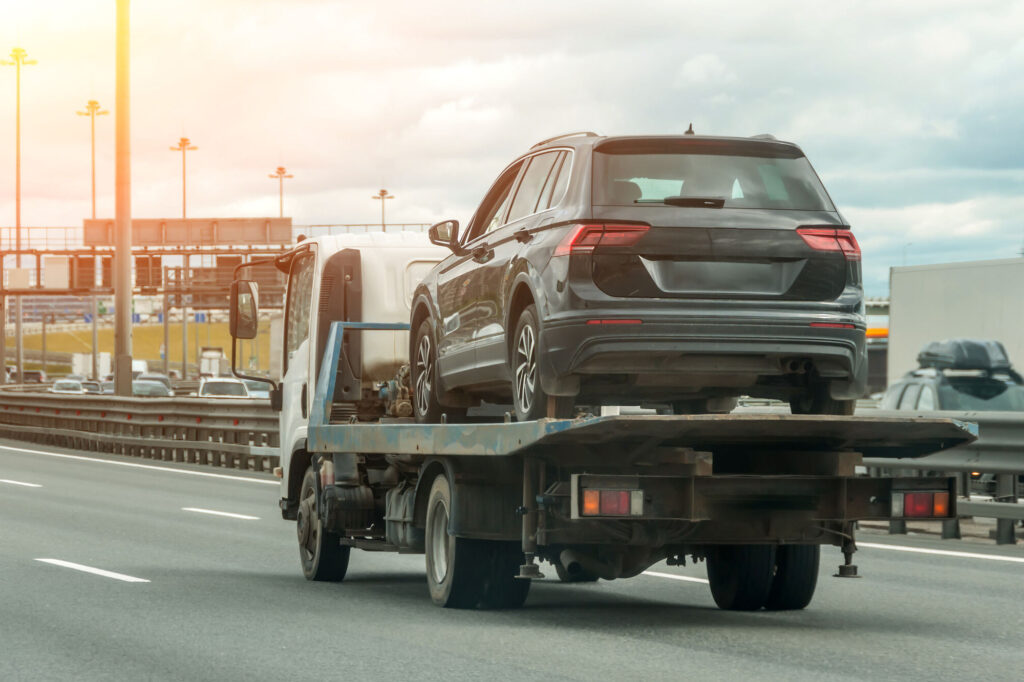 A non-road worthy car being transported on a truck