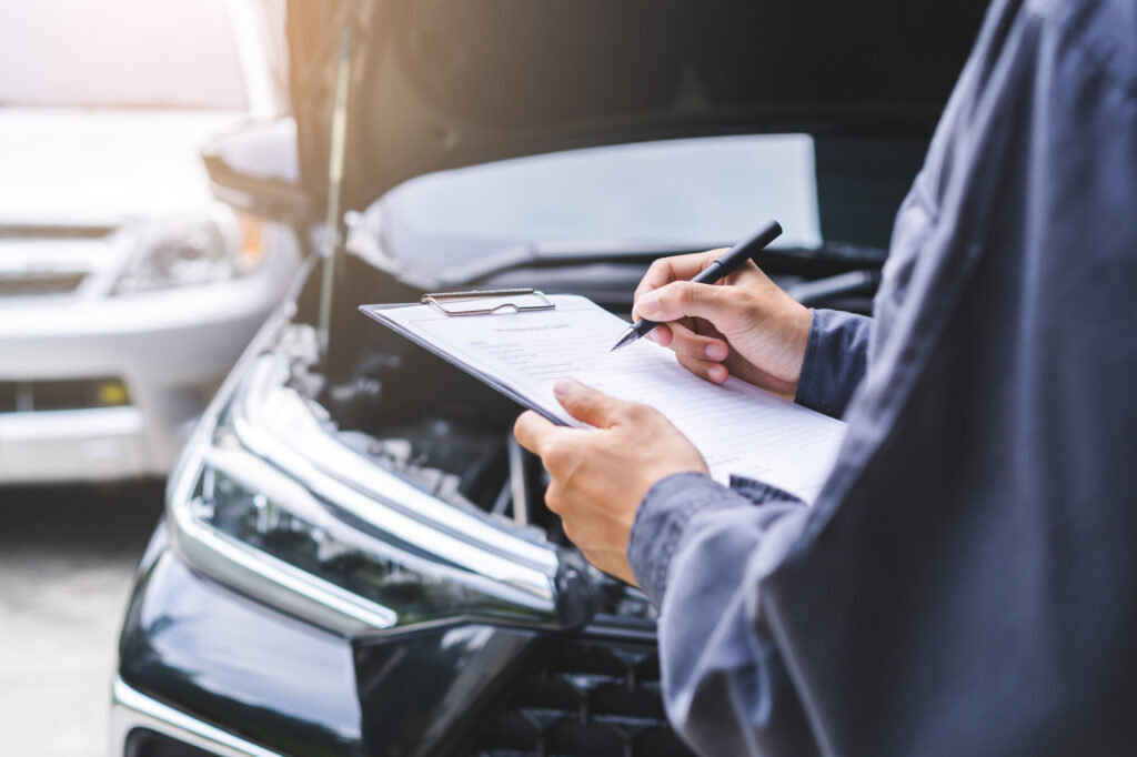 Image of man looking an older car with a clipboard in his hands