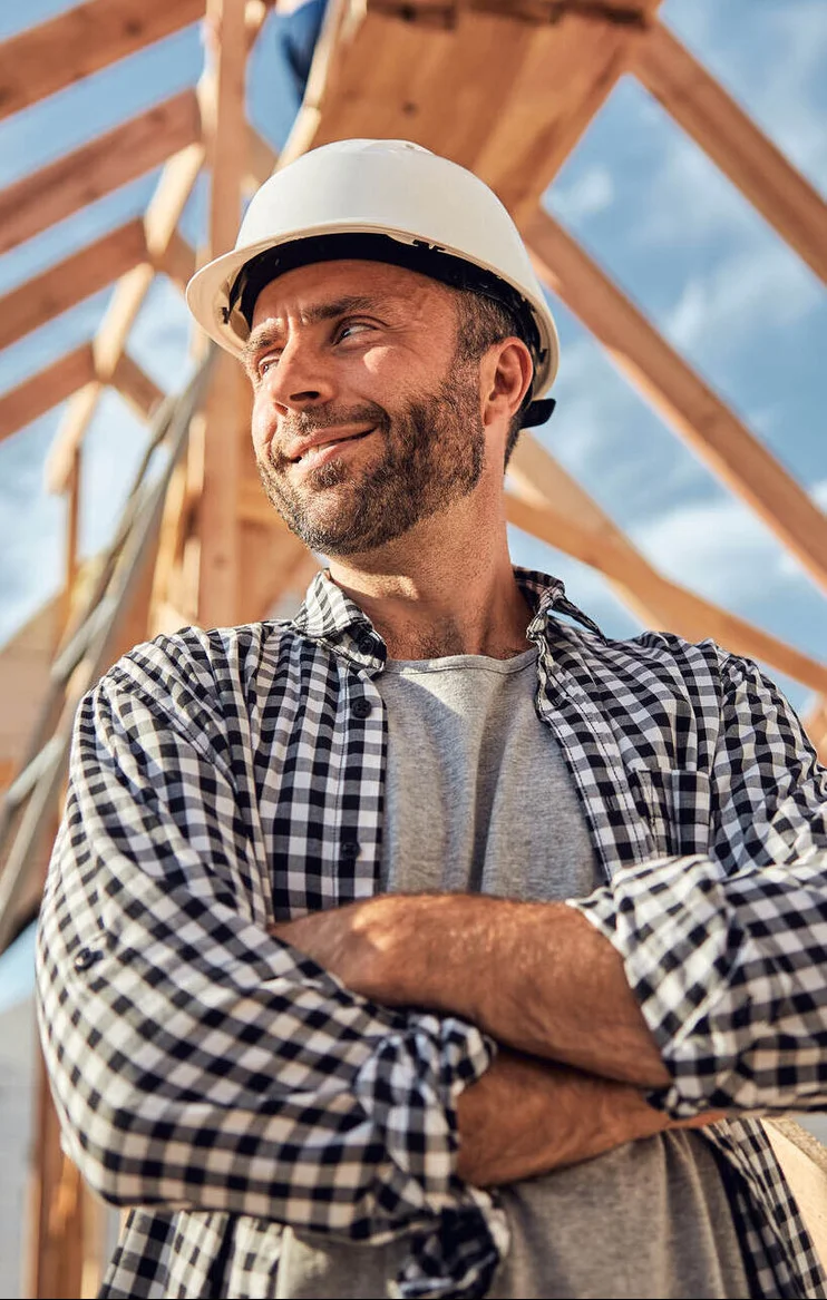 Builder or joiner stood under to the bare roof of a house