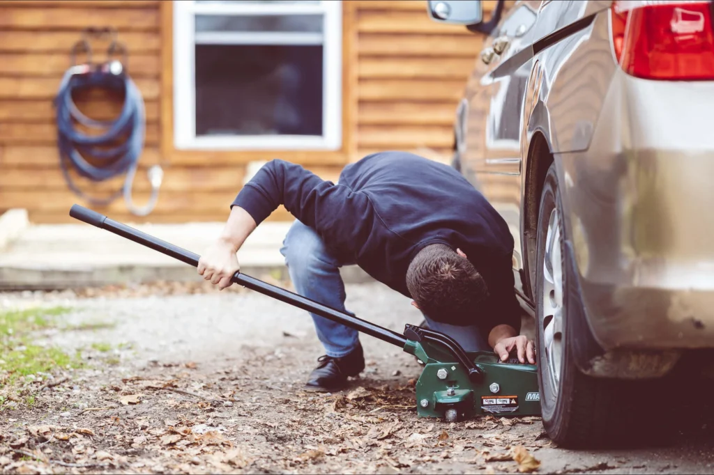 Man raising the side of a car in order to see underneath