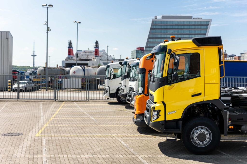 Several commercial courier vehicles lined up by the sea