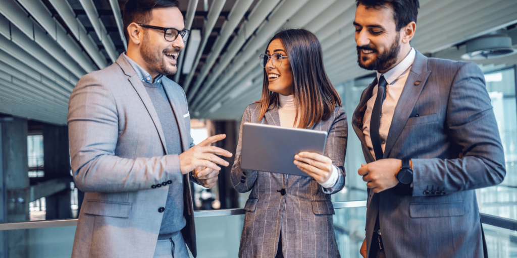 Group of professional business landlords discussing investment strategy in a commercial office building, using a digital tablet.
